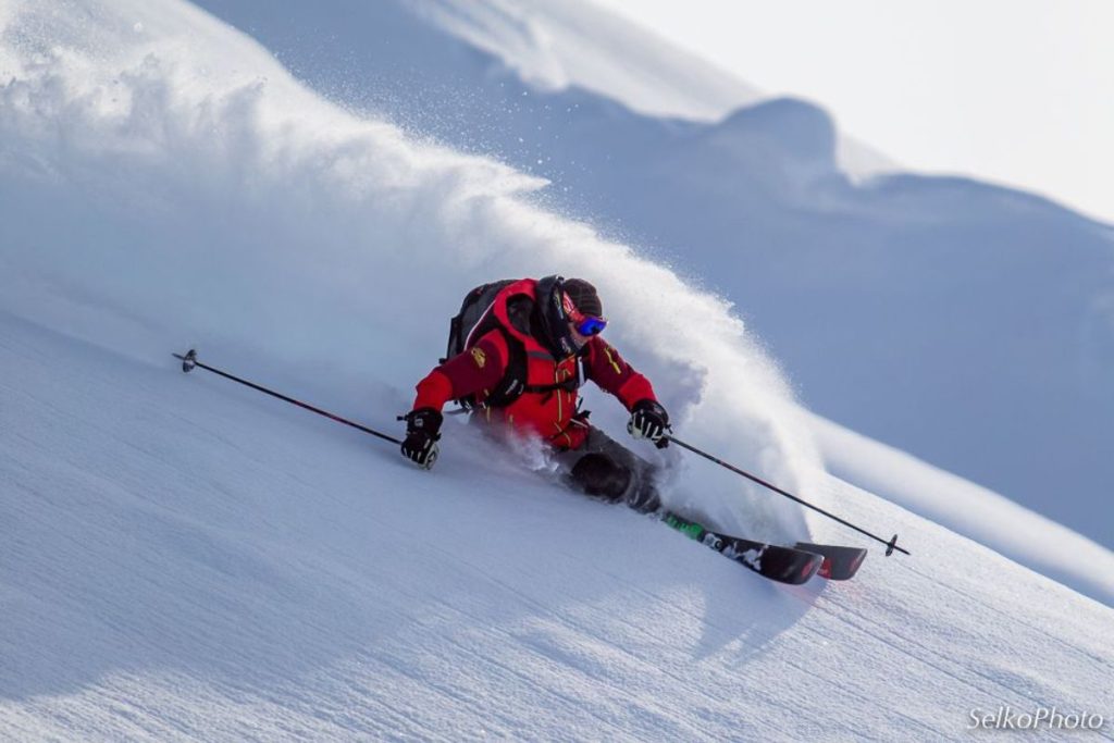 heli-ski-turning-through-deep-powdered-snow-min