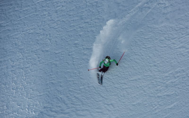heli-skiing-skier-carving-through-powdered-snow-min