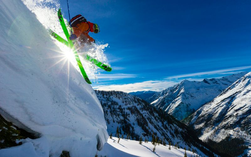 helicopter-skiing-skiers-getting-air-over-snow-min