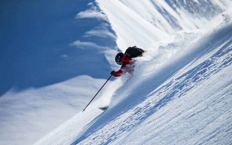heli-ski-skier-making-his-way-down-powdered-slope-min