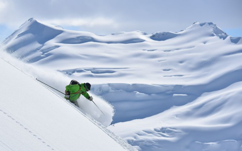 helicopter-skiing-carving-through-deep-powder-min